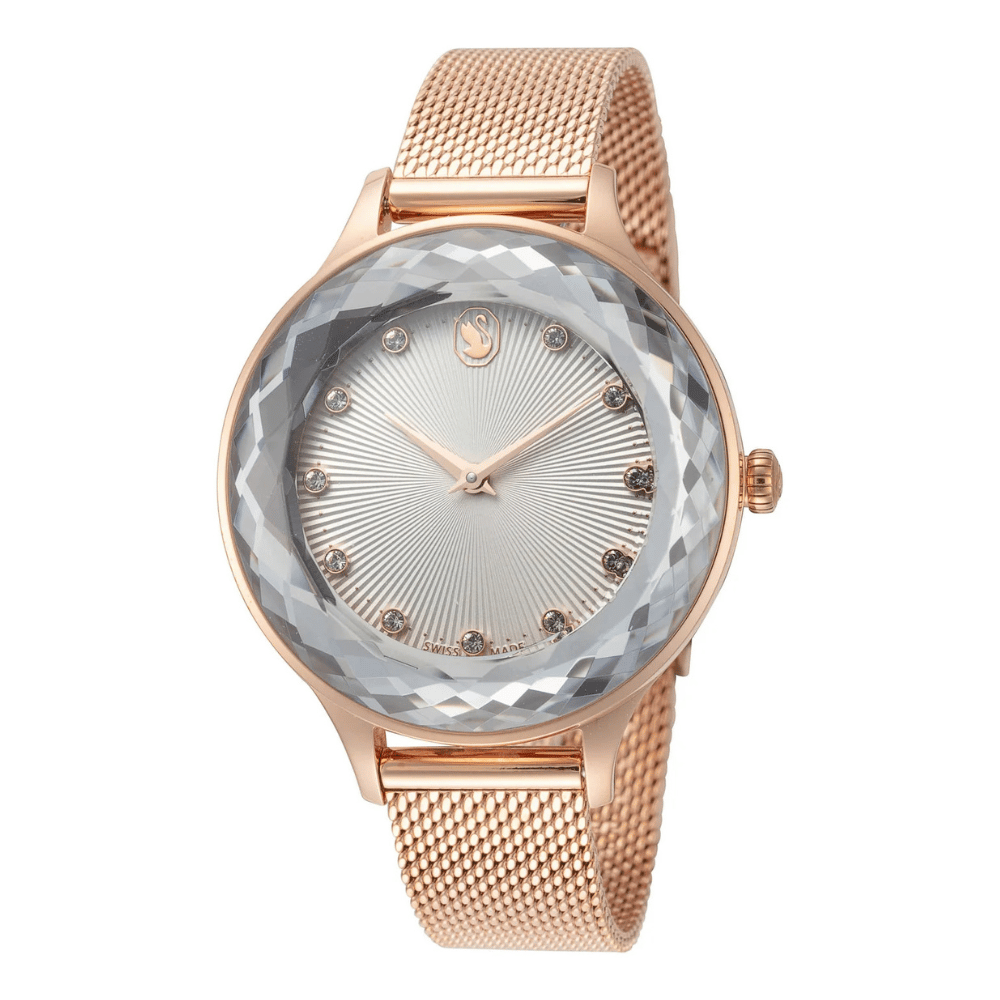A rose gold watch with a mesh band features a faceted crystal bezel, sunburst dial, and crystal hour markers.