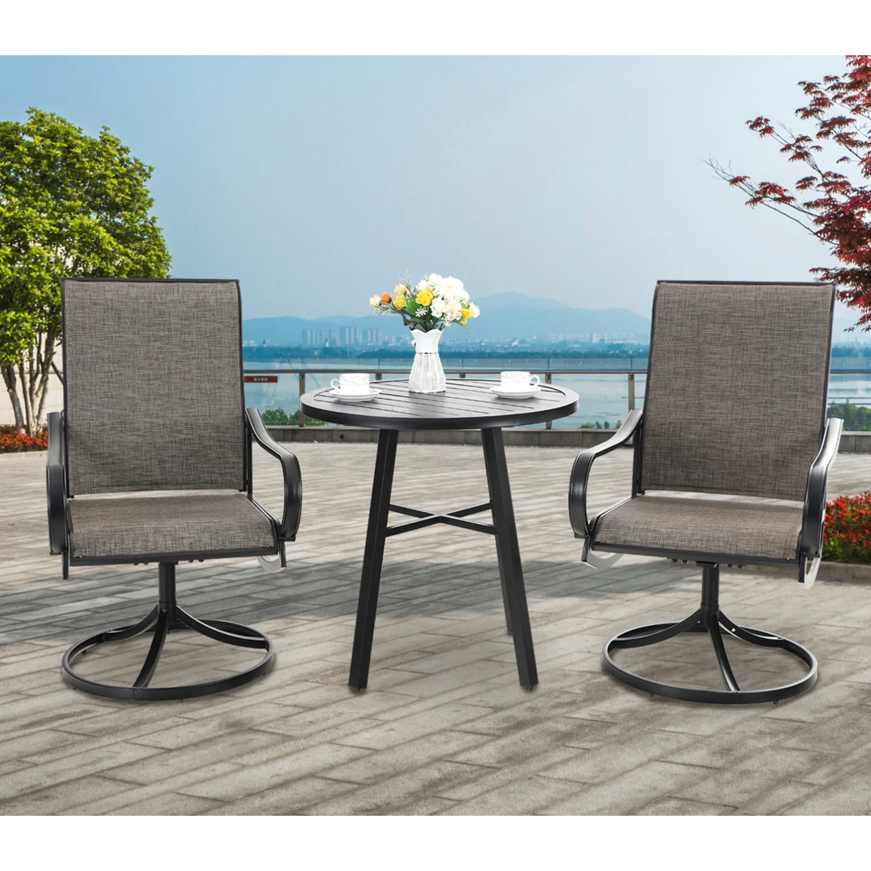 A 3-piece patio bistro set with two gray sling swivel chairs and a round black metal table featuring a striped tabletop. The table is decorated with a vase of flowers and two cups on saucers.