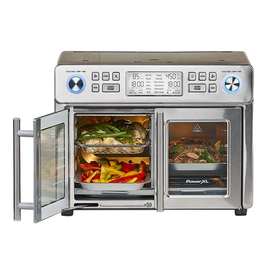 A stainless steel French door toaster oven with digital controls displays various cooking modes like air fry, roast, and grill. It's shown with food inside, including vegetables and meat, across two compartments for separate simultaneous cooking.