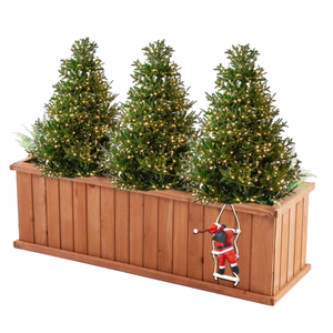 A 48-inch wooden planter box contains three artificial Christmas trees adorned with white lights. A small decorative Santa figure climbs a rope on the front of the box.