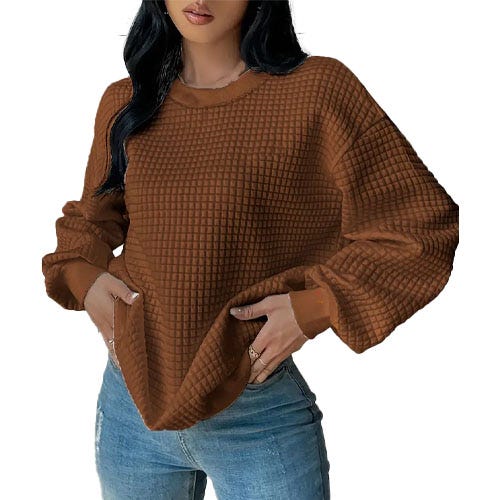 A person wears a brown, textured waffle-knit sweater paired with blue jeans.