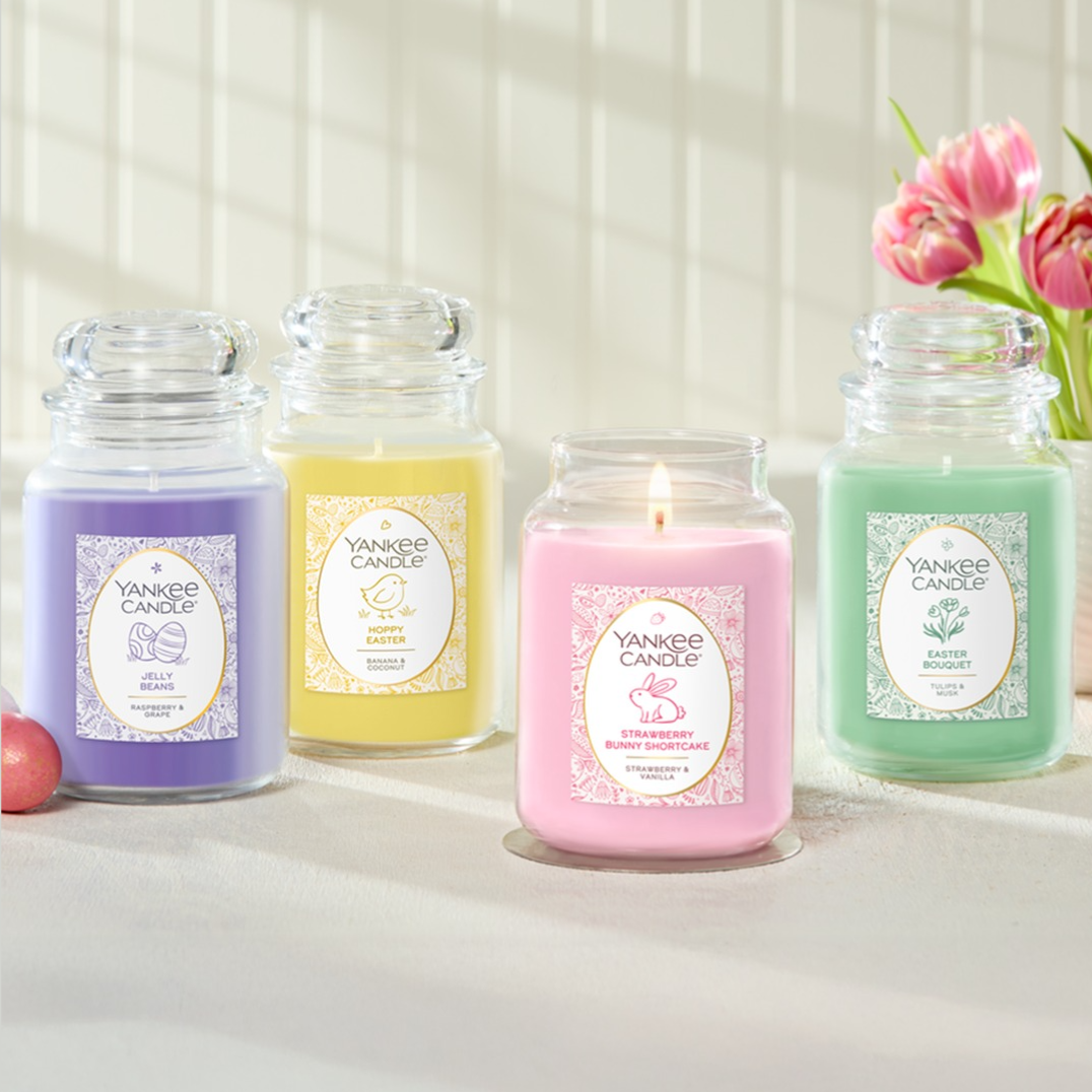 Four Yankee Candle jars in lavender, yellow, pink, and green are displayed. Scents include: Jelly Beans (Raspberry & Grape), Hoppy Easter (Banana & Coconut), Strawberry Bunny Shortcake (Strawberry & Vanilla), and Easter Bouquet (Tulips & Rose).