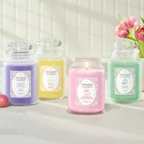Four Yankee Candle jars in lavender, yellow, pink, and green are displayed. Scents include: Jelly Beans (Raspberry & Grape), Hoppy Easter (Banana & Coconut), Strawberry Bunny Shortcake (Strawberry & Vanilla), and Easter Bouquet (Tulips & Rose).