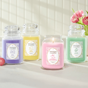 Four Yankee Candle jars in lavender, yellow, pink, and green are displayed. Scents include: Jelly Beans (Raspberry & Grape), Hoppy Easter (Banana & Coconut), Strawberry Bunny Shortcake (Strawberry & Vanilla), and Easter Bouquet (Tulips & Rose).