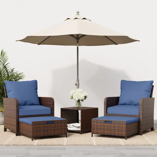 Outdoor patio set featuring two wicker chairs with blue cushions, matching ottomans, a small wicker table, a beige umbrella, and a vase of white flowers.