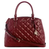 A red quilted handbag with two top handles, a detachable shoulder strap, and decorative charms. It features the GUESS logo on the front.