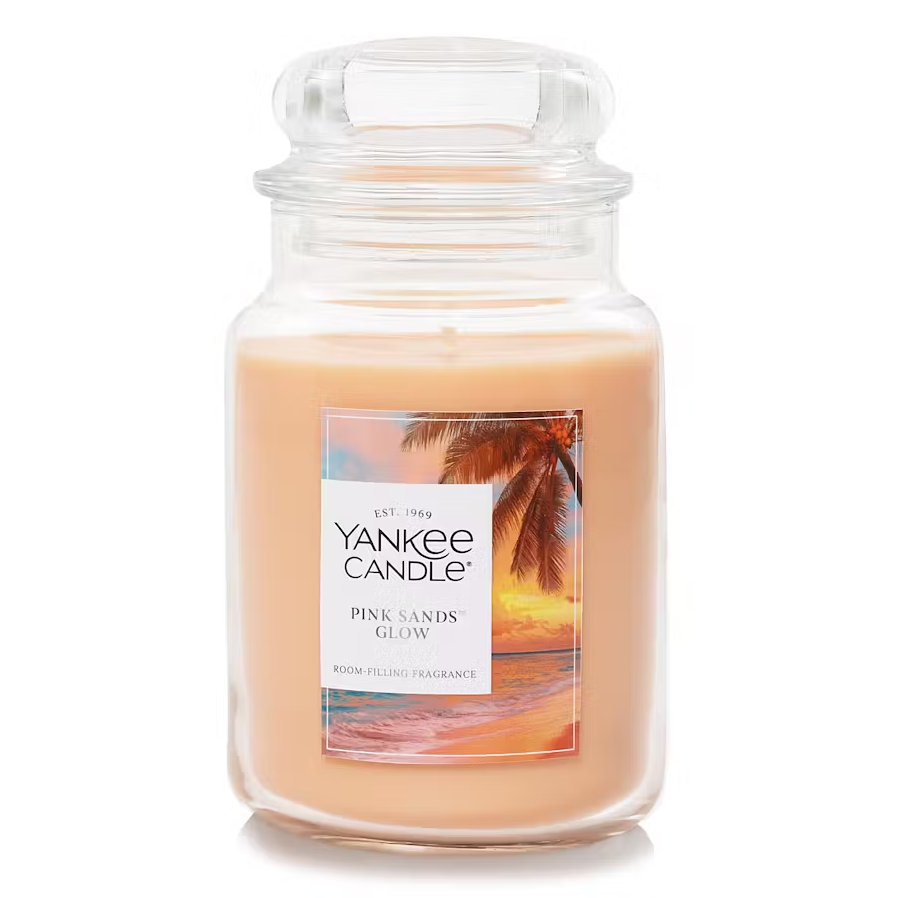 Large jar candle from Yankee Candle, Pink Sands Glow fragrance, featuring a tropical beach scene on the label. The wax is a light peach color, with a classic glass jar and lid design.