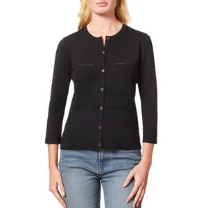 A woman is wearing a black knit cardigan with button closure and a crew neckline, paired with blue jeans.