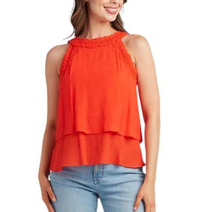 A sleeveless, layered orange top with lace trim around the neckline and shoulders, paired with light blue jeans.