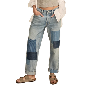 Lucky Brand Legend Mid-Rise Boy Jeans feature a relaxed fit with light wash denim and patchwork detailing. They have a casual, slightly distressed look and are paired with rolled cuffs and sandals.