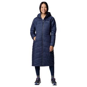A woman is wearing a long, navy-blue quilted coat with a hood, paired with dark leggings and athletic shoes. The coat has a full-length zipper and appears insulated for warmth.