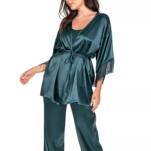 A three-piece set featuring a satin robe with fringe-trimmed sleeves and a waist tie, paired with a matching cami and pants in a deep green color.