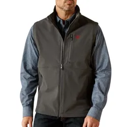 A man is wearing a gray zippered vest over a blue patterned long-sleeve shirt.