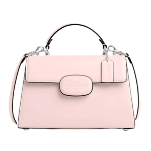 The Coach Eliza Top Handle Bag is a light pink structured handbag with a top handle and a detachable shoulder strap. It features silver-tone hardware, a front flap closure with the Coach logo, and a decorative tag hanging from the handle.