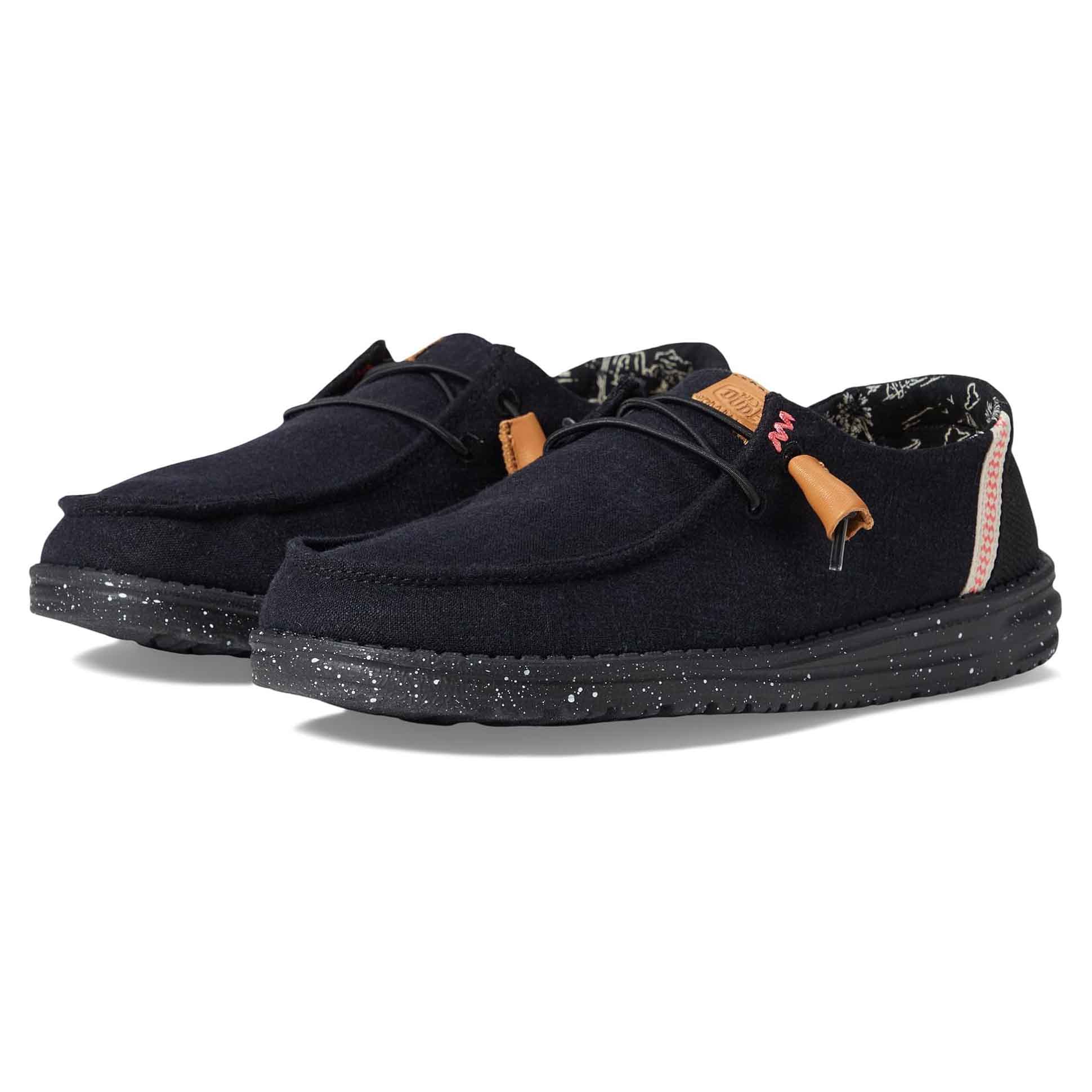 Hey Dude Wendy Washed Canvas Shoes feature a low-profile slip-on design in black with speckled soles, leather accents, and cushioned insoles for comfort.