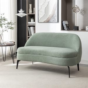 A light green loveseat with a curved backrest and plush texture, set on slim black metal legs. It's placed in a modern living room with neutral tones and minimalist decor elements.