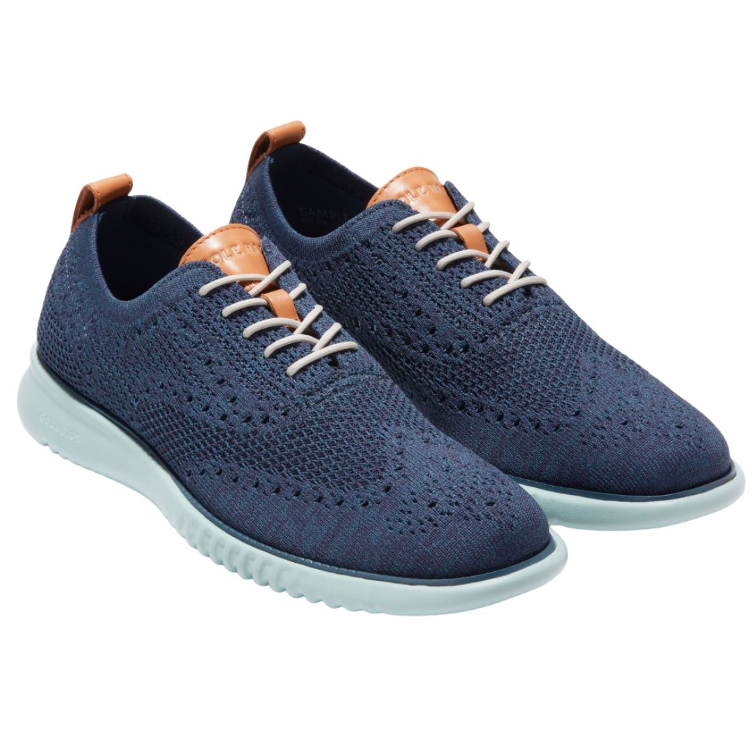 Navy blue knitted oxford shoes with light blue soles and tan leather accents on the tongue and heel tab.