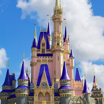 A castle with blue and gold spires against a blue sky with clouds.