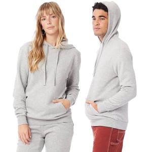 Two models are wearing light gray hoodies with front pockets, one paired with matching sweatpants, and the other with red pants.