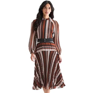 A woman wears a long-sleeved, knee-length dress with a geometric pattern in red, black, and white, featuring a high neck and a black belt.