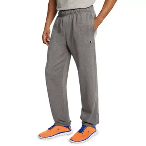 Gray Champion fleece pants with an elastic waistband and side pockets, featuring the Champion logo on the left thigh. Paired with bright orange and blue athletic shoes.
