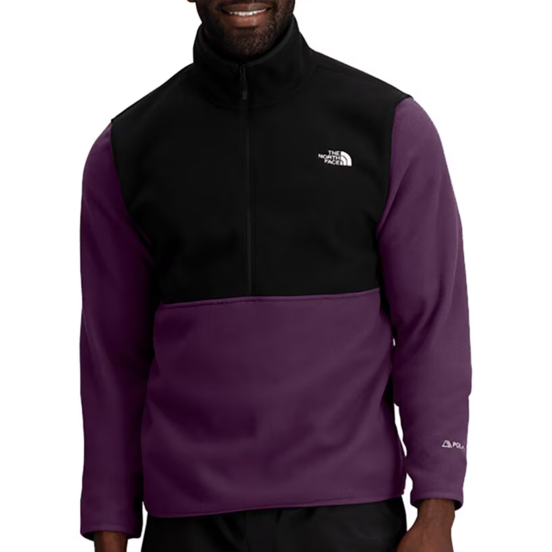 A man wearing a black and purple zip-up fleece jacket with logo embroidery on the chest and sleeve.