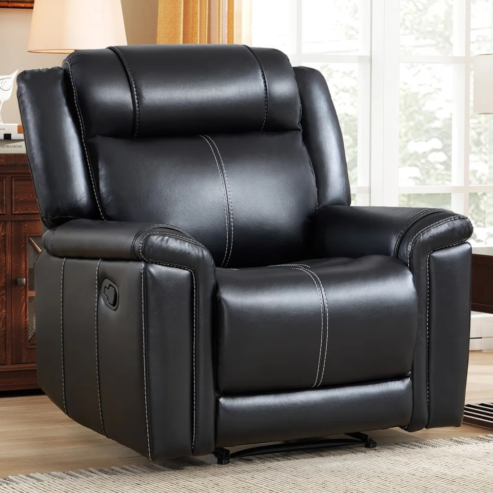 A black leather recliner with white stitching is in a living room setting, featuring a classic design with a manual reclining lever on the side.
