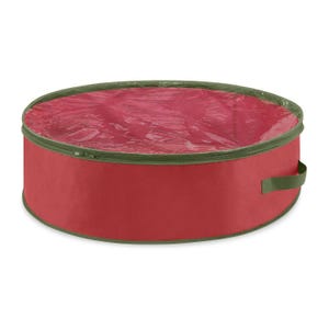 A round, red wreath storage bag with a transparent plastic top and green trim. It includes a green handle for easy carrying and a zipper closure.