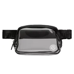 A clear, compact waist pack with a black strap and zipper, featuring a logo on the front corner.