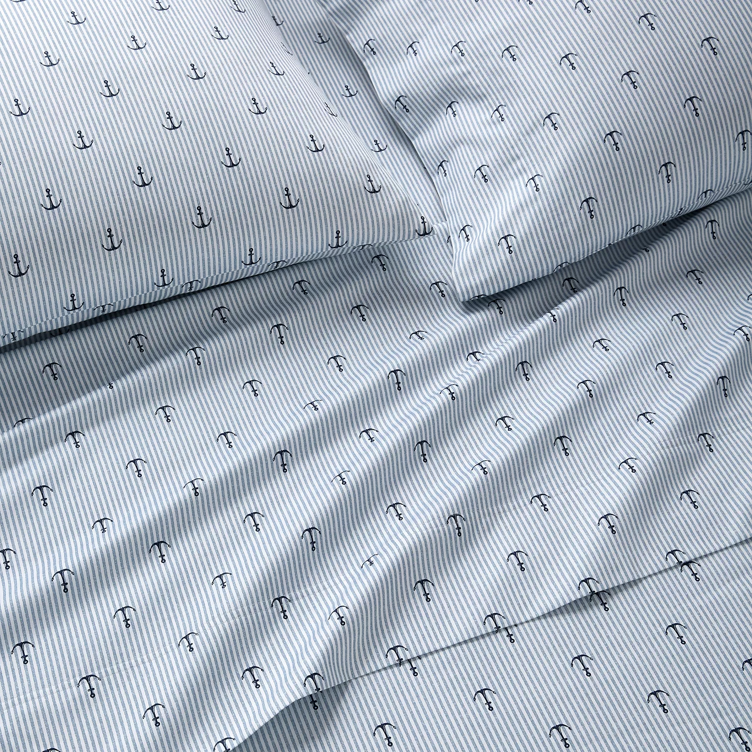 Bedding set with a nautical theme featuring blue and white stripes and small anchor designs.