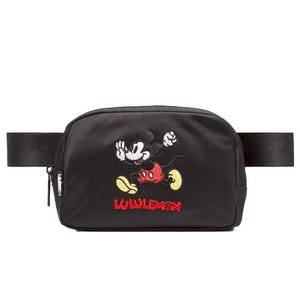 A black Lululemon belt bag featuring an embroidered Mickey Mouse design and the Lululemon logo.
