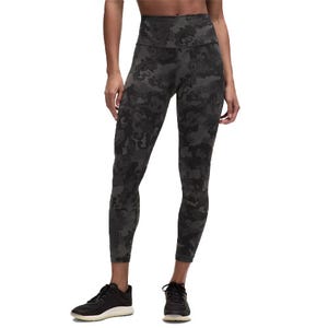 High-waisted leggings with a dark camouflage pattern, paired with black athletic shoes.