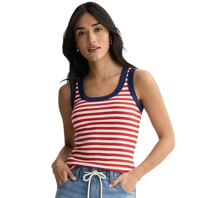 A woman wears a sleeveless red and white striped tank top with navy trim, paired with light blue drawstring pants.