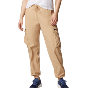 Columbia Boundless Trek Cargo Pants in beige feature a drawstring waist, side cargo pockets, and elastic cuffs, paired with blue sneakers.