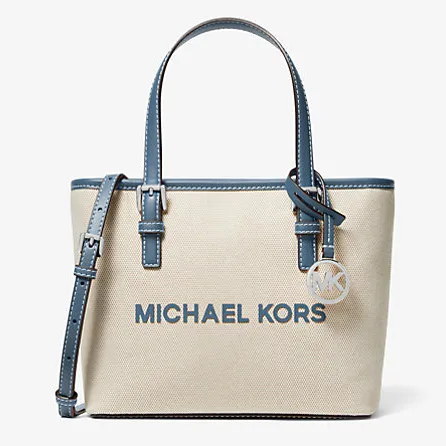 Beige canvas tote bag with navy blue leather trim and handles, featuring the Michael Kors logo on the front and a detachable strap with an MK charm.