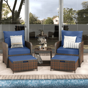 Outdoor seating set with two wicker armchairs, blue cushions, matching ottomans, and a side table, all positioned by a pool.