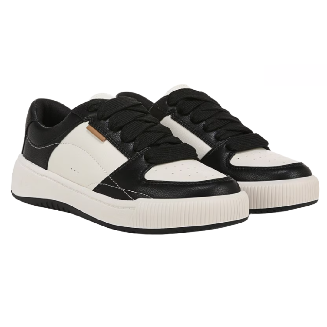 Dr. Scholl's Ollie Sneakers are low-top shoes featuring a black and white color scheme. They have black laces, perforated detailing on the toe, a textured white sole, and a small metal accent on the side.