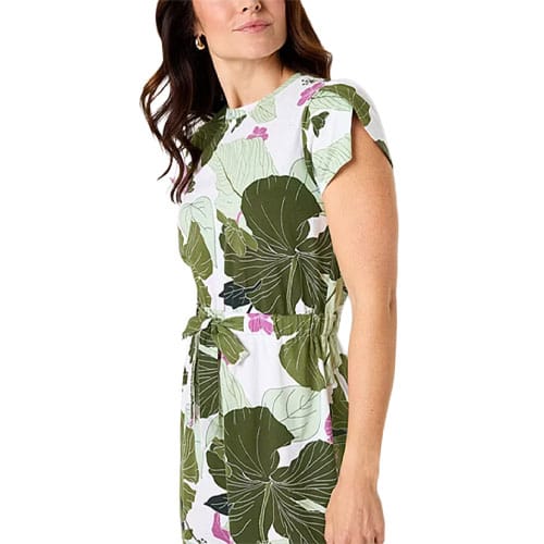 A woman wearing a white dress with large green leaf and pink flower prints, featuring short sleeves and a tied waist.