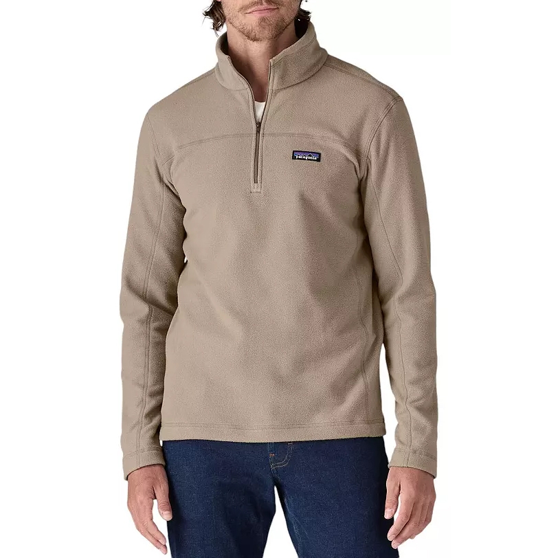 A beige Patagonia fleece pullover with a quarter-zip, worn by a model, paired with blue jeans.