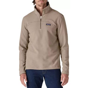 A beige Patagonia fleece pullover with a quarter-zip, worn by a model, paired with blue jeans.
