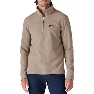 A beige Patagonia fleece pullover with a quarter-zip, worn by a model, paired with blue jeans.
