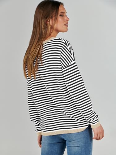 A woman is wearing a striped black and white long-sleeve top paired with blue jeans.