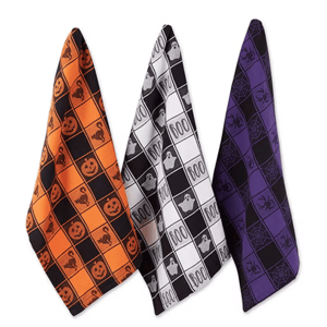 Three Halloween-themed kitchen towels feature designs with pumpkins and cats on orange, ghosts and \“BOO\“ on black and white, and spiders and webs on purple.
