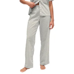 A person is wearing gray and white checkered pajamas, including a short-sleeved top and long pants. The pajamas feature a relaxed fit and are being worn barefoot.