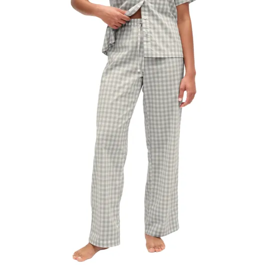 A person is wearing gray and white checkered pajamas, including a short-sleeved top and long pants. The pajamas feature a relaxed fit and are being worn barefoot.
