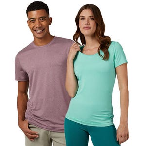 A man and a woman wearing casual t-shirts, one in light purple and the other in mint green, paired with beige pants and teal leggings, respectively.