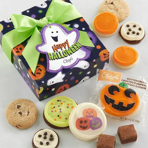 Halloween-themed gift box with a green bow, surrounded by frosted and chocolate chip cookies, brownies, and a pumpkin-shaped buttercream frosted cookie.