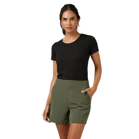 A woman is wearing a black T-shirt paired with high-waisted olive green shorts and white sneakers.