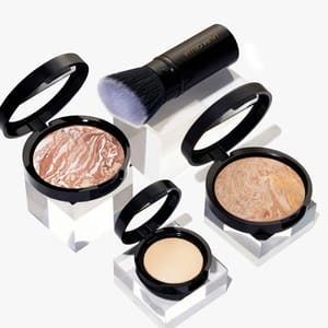 Makeup items including two marbled highlighters, a compact face powder, and a makeup brush.