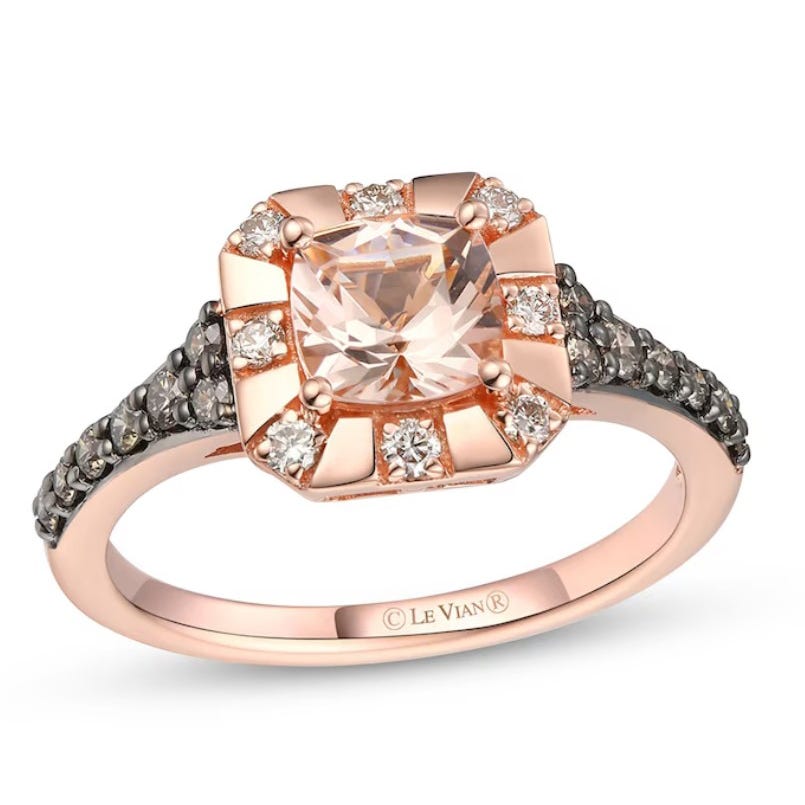 A rose gold ring featuring a cushion-cut center stone, surrounded by smaller round diamonds, with additional dark stones set along the band.